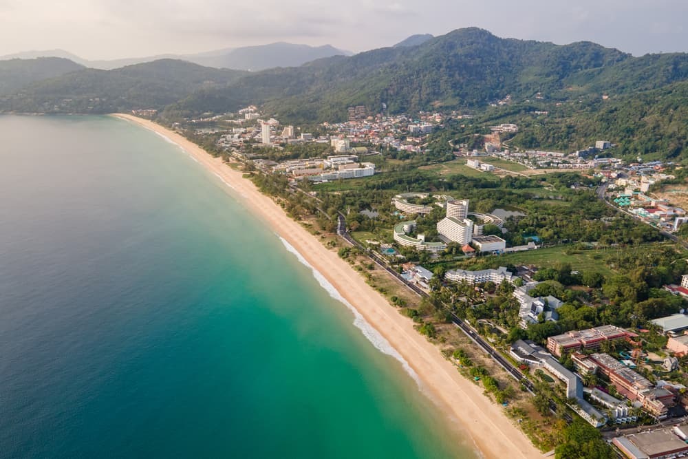 Aerial view of Karon’s white sand beach, turquoise-blue waters, and beachfront hotels